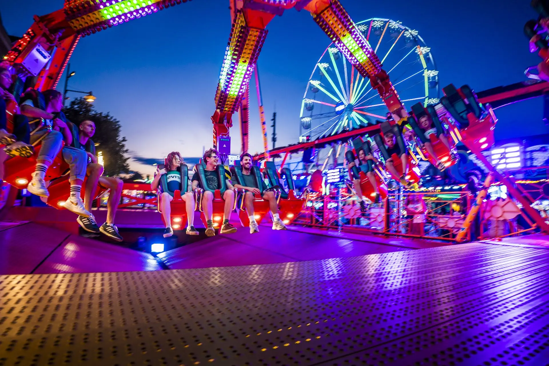 Verlichte kermisattractie met bezoekers in de avond